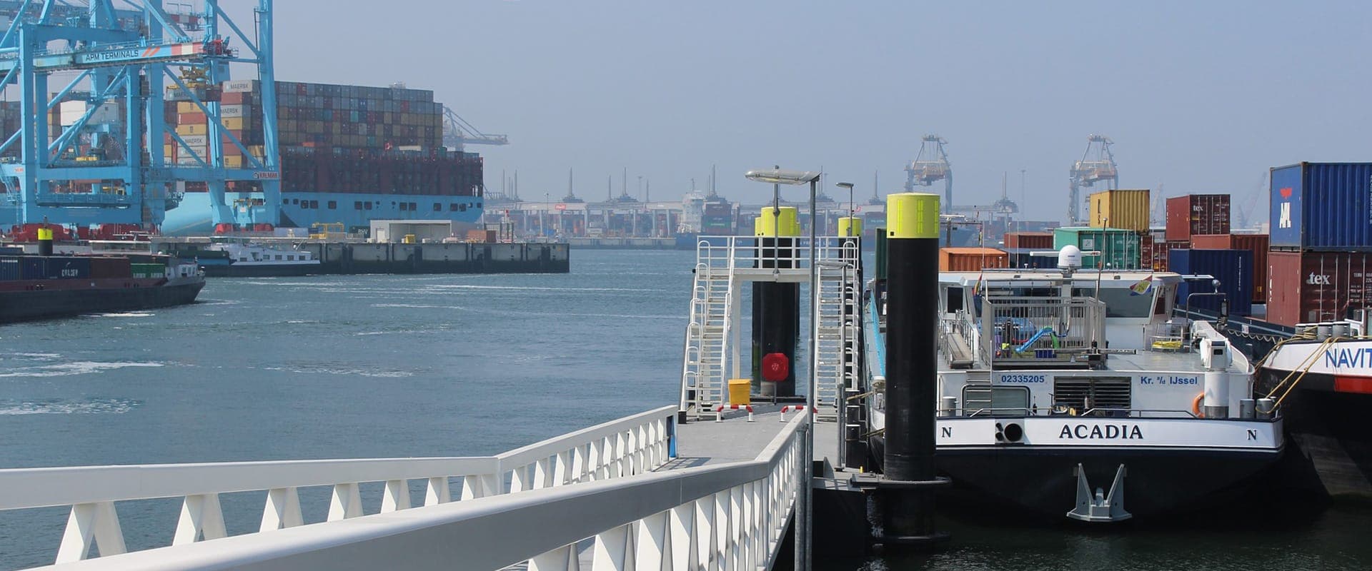 Moderne haveninfrastructuur met aanlegsteiger voor de binnenvaart en op de achtergrond een internationale containerterminal voor logistieke overslag.